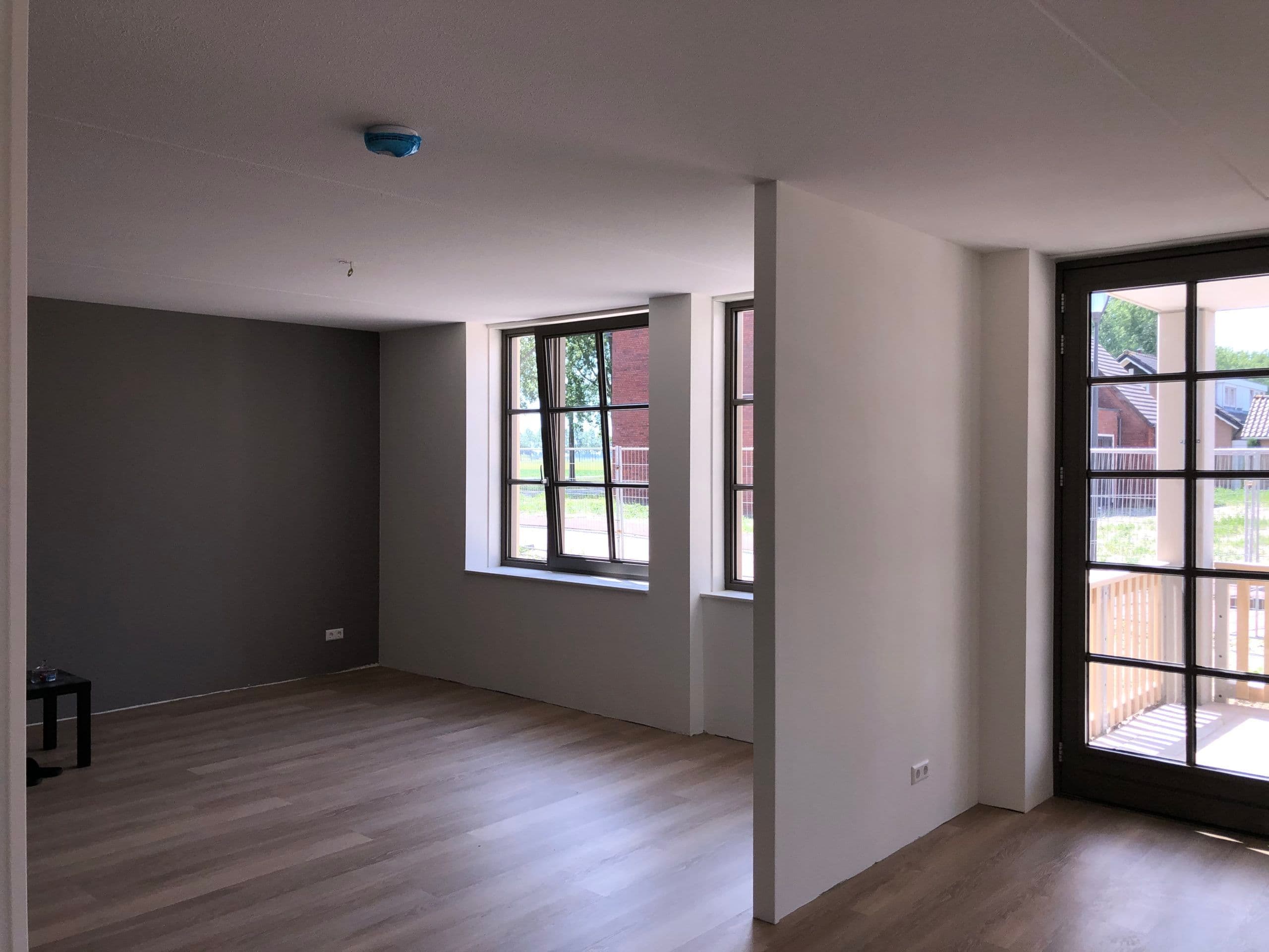 Strak afgewerkte grijze accentmuur na behandeling door P. Verberg